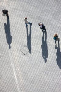 people walking on pavement and their shadows